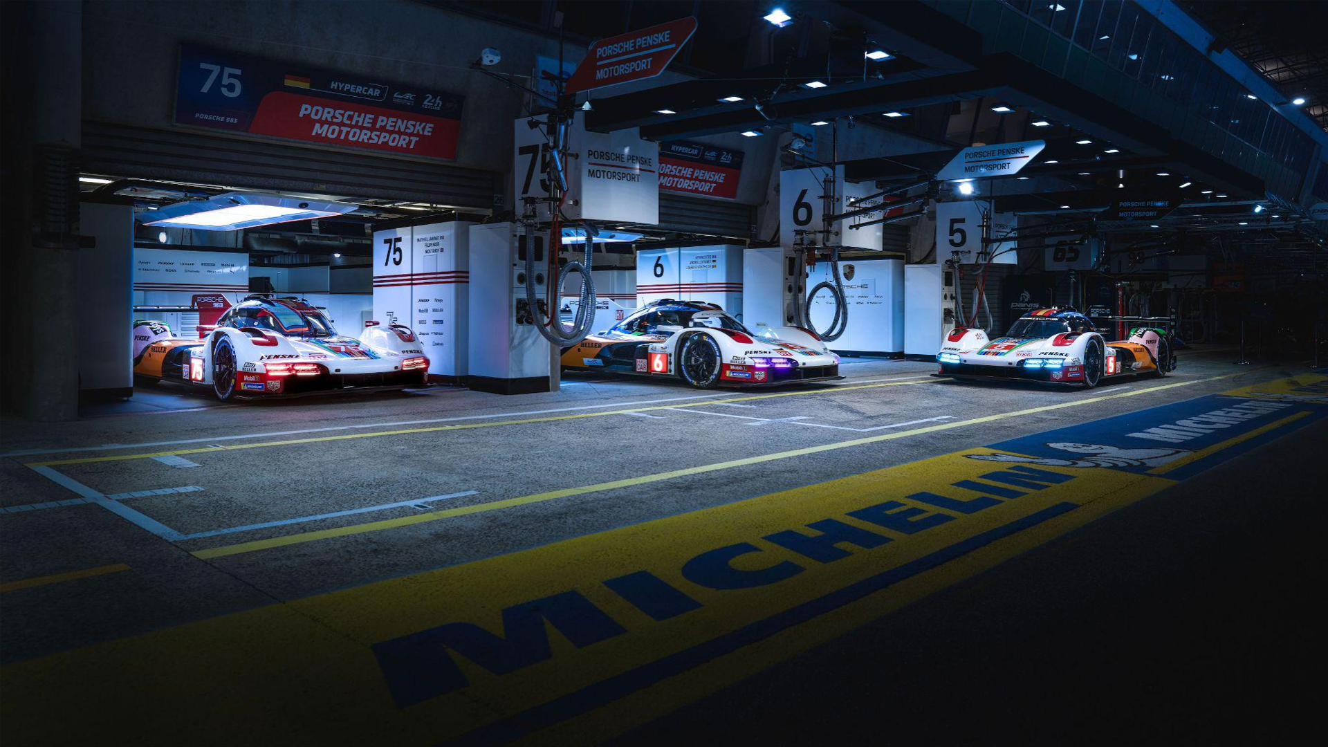 Three Porsche 963 LMH Prototypes in pit lane
