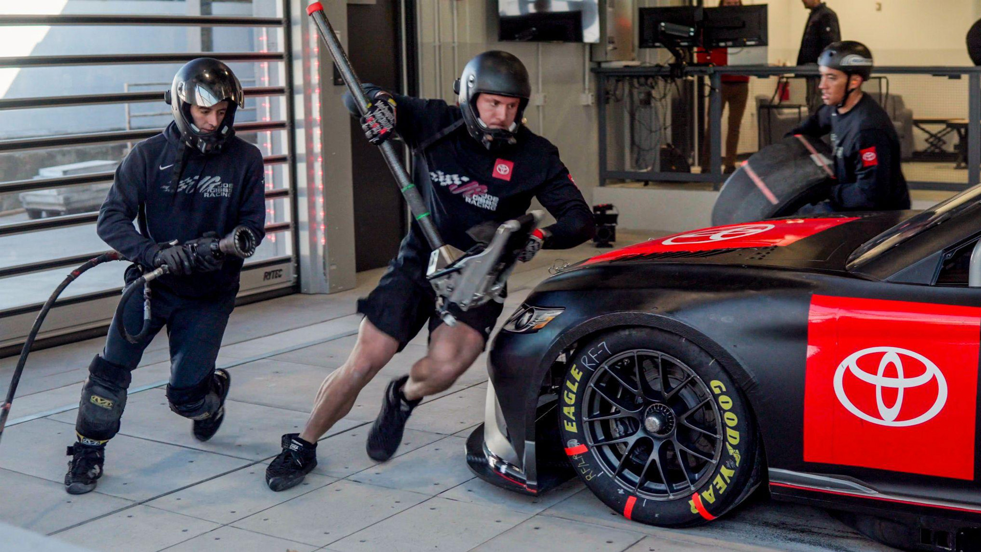 Pitcrew members in action getting ready to change the left-hand side tyres at JGHPI lab