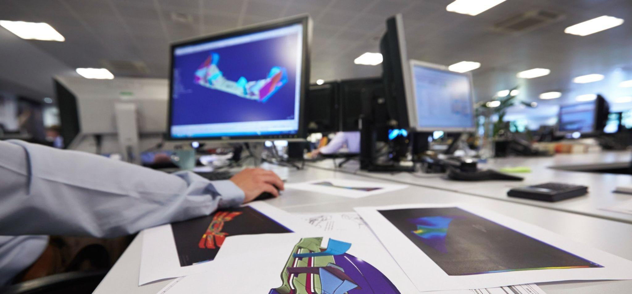 F1 engineer looking at a 3D render of a front wing on a computer