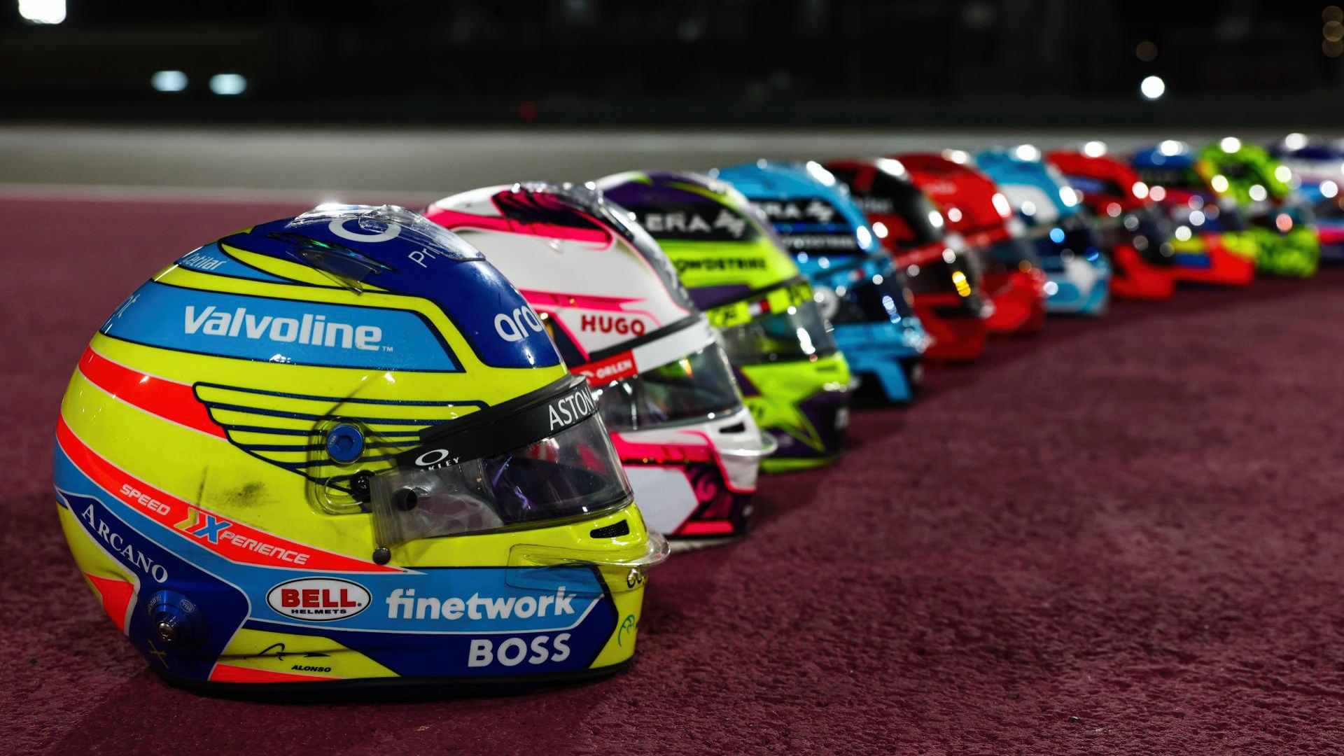 2024 Formula 1 drivers' helmets lined up on the ground