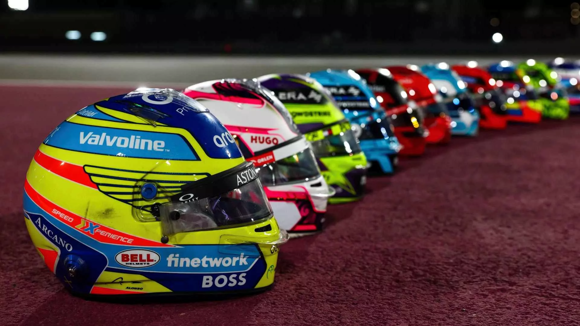 2024 Formula 1 drivers' helmets lined up on the ground