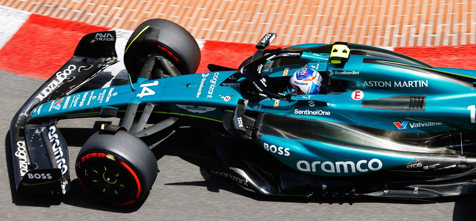 Green Aston Martin AMR24 F1 car from a high angle with a red and white kerb in the background
